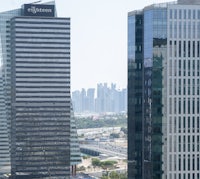 Doha’s skyline seen through the high-rise buildings of the West Bay district, featuring the modern “The Eighteen” tower in Lusail Marina.